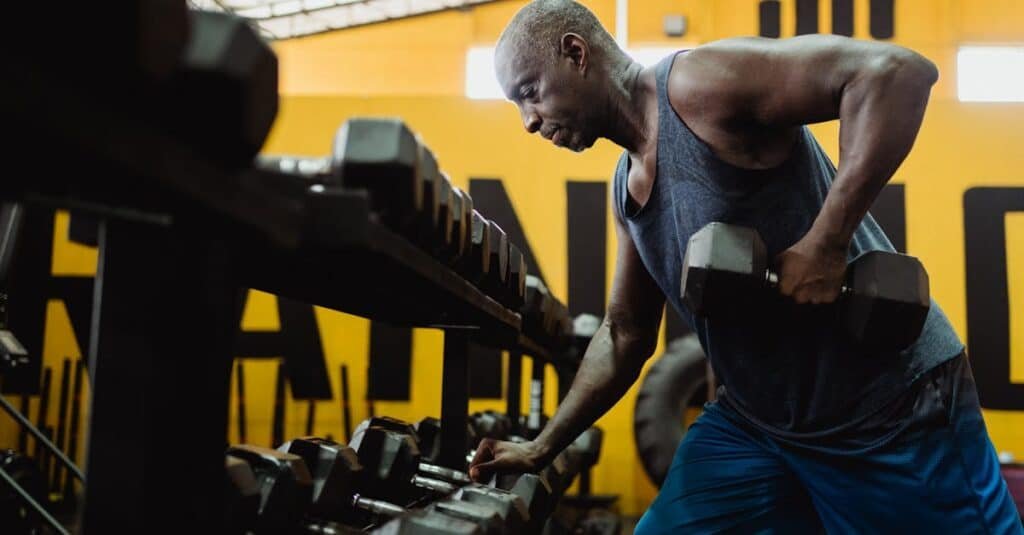 Athletic man lifting dumbbells in a gym for strength training workout.